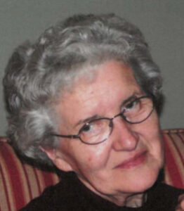 Elderly woman with glasses and short gray hair.