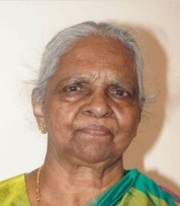 Elderly woman with gray hair and colorful saree.