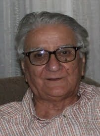 Elderly man with glasses sitting indoors