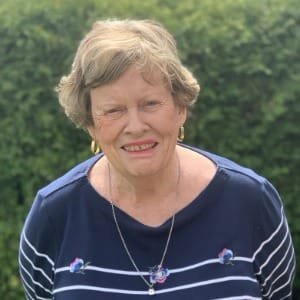 Elderly woman smiling outdoors.