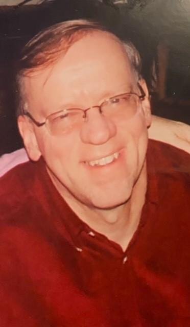 Smiling man in glasses and red shirt