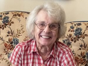 Smiling woman in glasses on floral couch