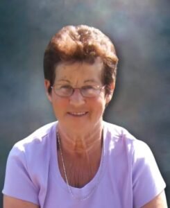 Smiling woman in glasses with short hair and lavender shirt.