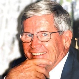 Smiling elderly man with gray hair and glasses.