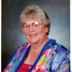 Smiling woman in colorful jacket and glasses.