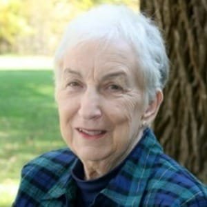 Elderly woman smiling outdoors near a tree