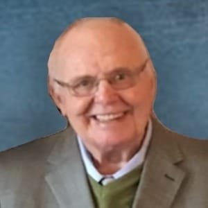 Smiling elderly man in suit and glasses.