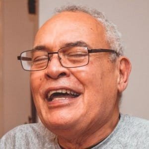 Elderly man laughing joyfully with glasses.