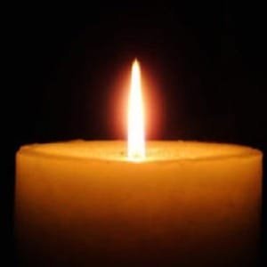 Lit candle in the dark, soft glow.