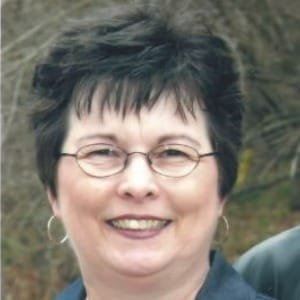 Smiling woman with glasses and short hair.