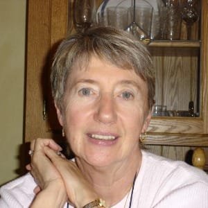 Smiling woman sitting in front of wooden cabinet.
