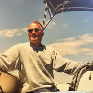 Person sailing a boat under sunny skies.