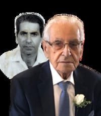 Elderly man with historical photo in background.