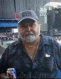 Man at outdoor concert holding a soda can.