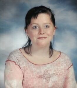 Young person smiling against sky background.