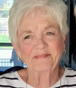 Elderly woman with short white hair smiling.