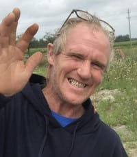 Man smiling and waving in a field