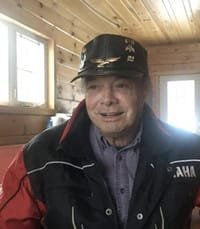 Man wearing jacket and cap indoors.