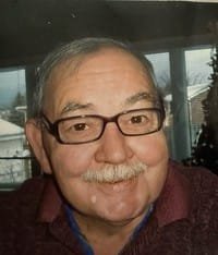 Smiling man with glasses and mustache indoors