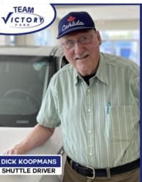 Shuttle driver smiling next to vehicle indoors.