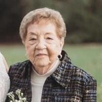 Elderly woman smiling in outdoor setting.