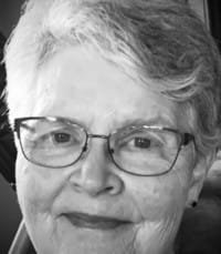 Elderly woman smiling with glasses.
