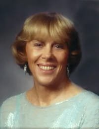 Smiling woman with short blonde hair and earrings.