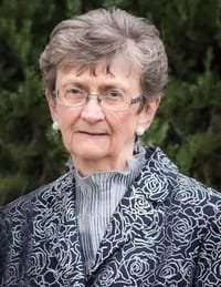 Elderly woman with glasses, wearing floral-patterned jacket