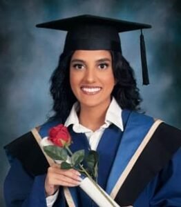 Graduate holding diploma and red rose, smiling.