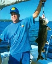 Man proudly holding caught fish on boat.