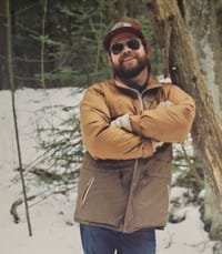 Man in winter jacket and hat in forest