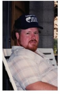 Man wearing a cap sitting on a chair.