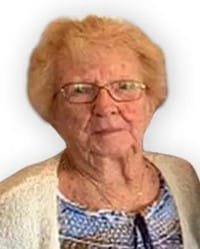 Elderly woman with glasses in patterned shirt.