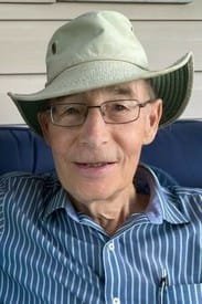 Elderly man wearing a hat and glasses smiling.