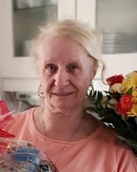 Smiling woman holding colorful flowers indoors.