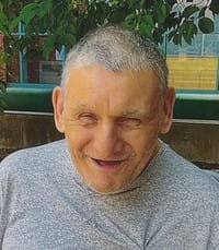 Smiling man outdoors in a gray shirt