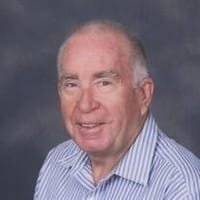 Elderly man smiling in a striped shirt portrait.