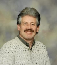 Smiling man with mustache and sweater, portrait photo.