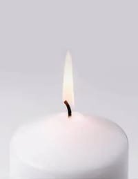 Lit white candle on a grey background.