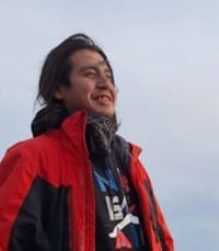 Smiling person in red jacket outdoors.