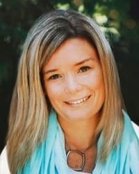 Smiling woman with blonde hair and blue scarf.