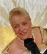 Smiling woman in formal attire and pearls