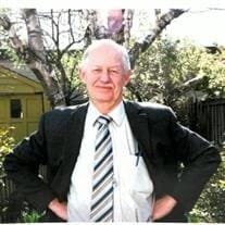 Man in suit standing outdoors by a tree.