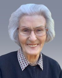 Smiling older woman with glasses and gray hair.