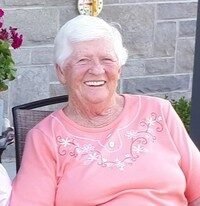 Smiling woman in pink shirt on patio chair.