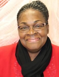 Smiling person with glasses and red shirt.