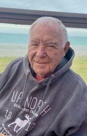 Smiling man in a gray hoodie by the sea.