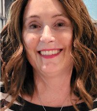 Smiling woman with wavy hair indoors.