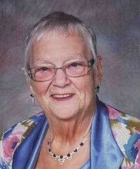 Smiling elderly woman wearing glasses and colorful shawl.