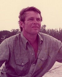Person outdoors in casual shirt, serene background.